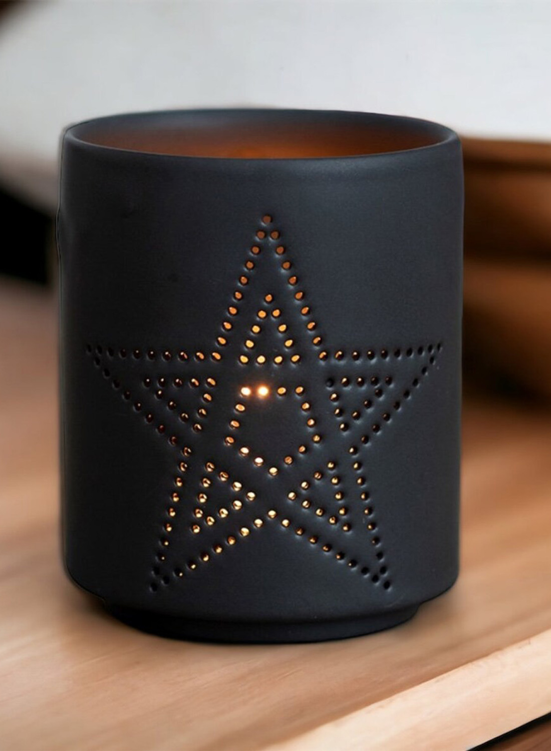 Pentagram lysholder – sort cylindrisk lysholder med et perforeret pentagram, der slipper varmt lys igennem. Gotisk dekoration med mat finish.