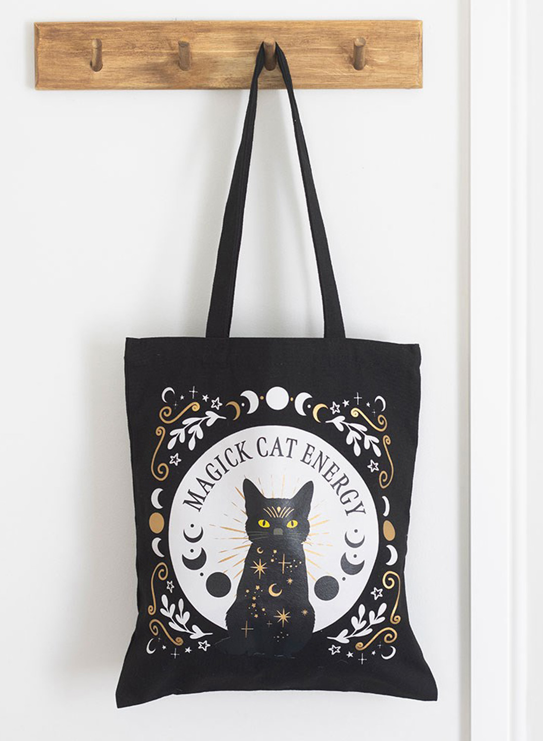 Black Magick Cat Energy Tote Bag - sort stoftaske i polyester med kattemotiver, gule øjne, månefaser og stjerner. Mål 38,5 × 33,8 cm.